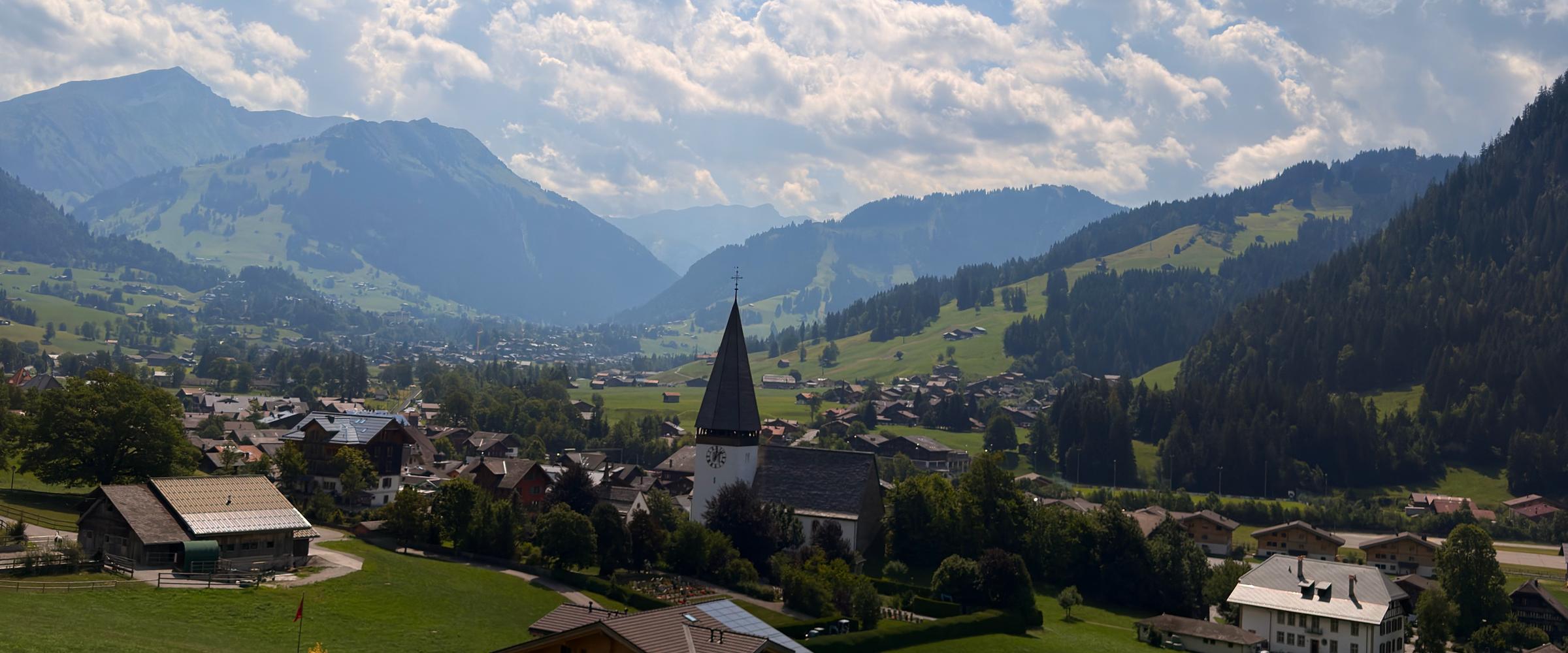 A Bernese Oberland village of chalets around a church spire, with ridge behind ridge fading south